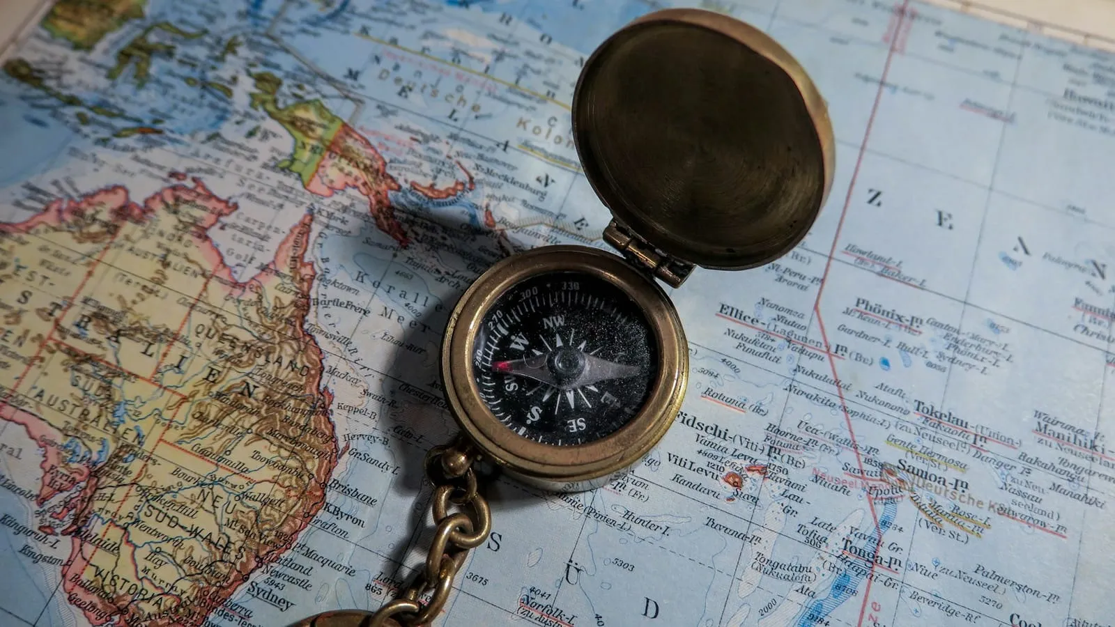 A brass compass lying open on a world map